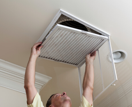 John Betlem Heating and Cooling, Inc. technician installing air filter. 