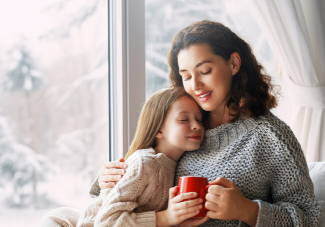 Mother and daughter enjoying winter nature in the window